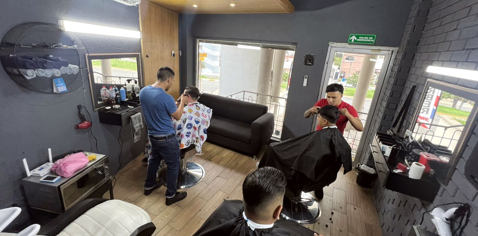 Barberos atendiendo a un niño y a un adulto al mismo tiempo dentro del estudio Razor House
